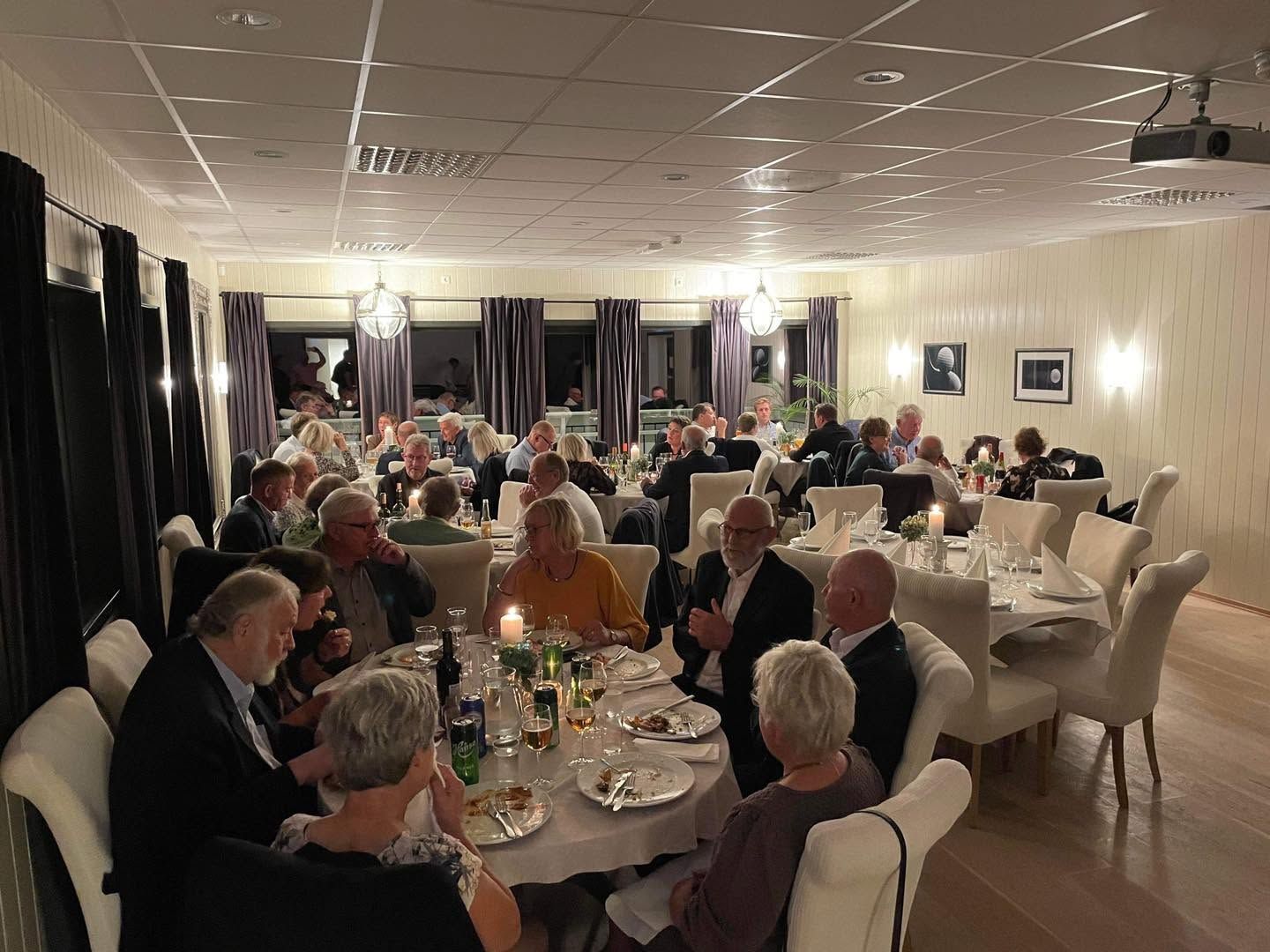 Fullsatt selskapssal på Haugesund Golfpark med gjester ved runde bord og levende lys